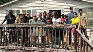 A large group of people gathered on a porch in front of a house
